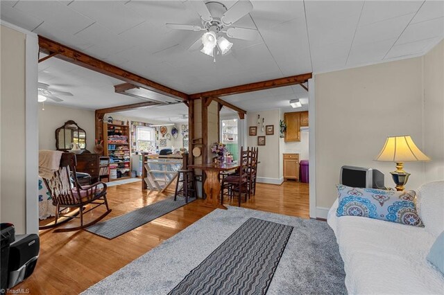 living room featuring ceiling fan, beamed ceiling, and light wood-type flooring