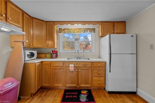 kitchen with crown molding, sink, white appliances, and light hardwood / wood-style flooring