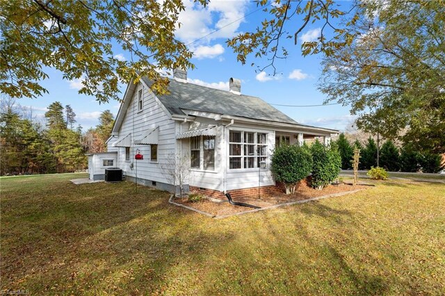 view of side of property featuring central AC unit and a yard