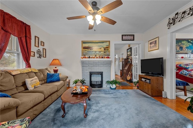 living room featuring hardwood / wood-style flooring, ceiling fan, and a fireplace