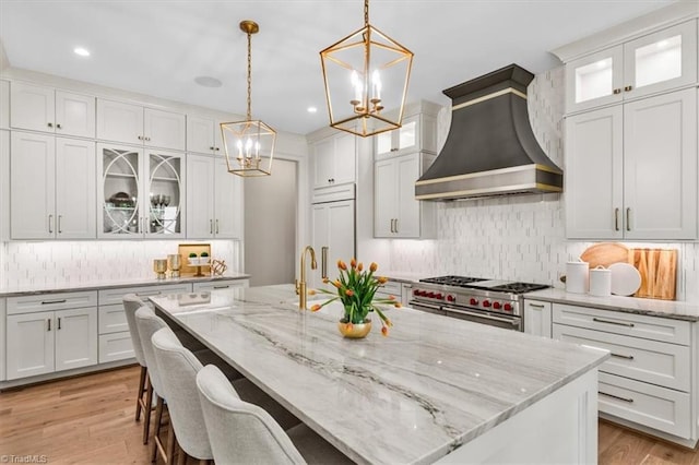 905 Brookside Dr, Greensboro, NC 27408 - kitchen with white cabinets, tasteful backsplash, a notable chandelier, high quality appliances, and premium range hood