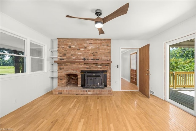 unfurnished living room with light hardwood / wood-style floors, ceiling fan, and a brick fireplace