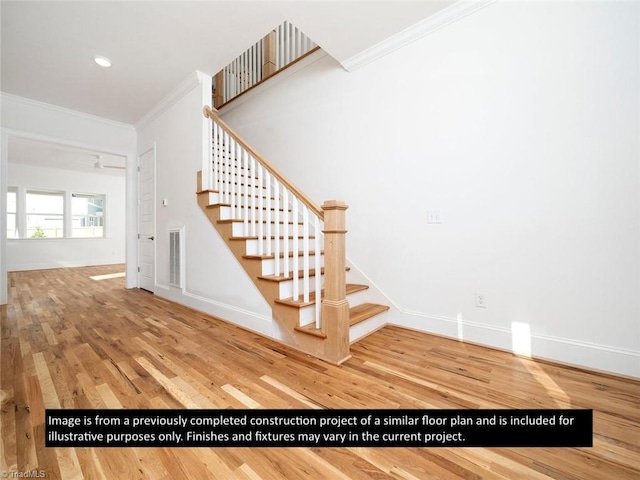 stairs with hardwood / wood-style floors, ceiling fan, and crown molding