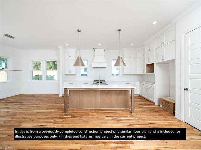 kitchen featuring premium range hood, a kitchen island with sink, white cabinetry, and light hardwood / wood-style flooring