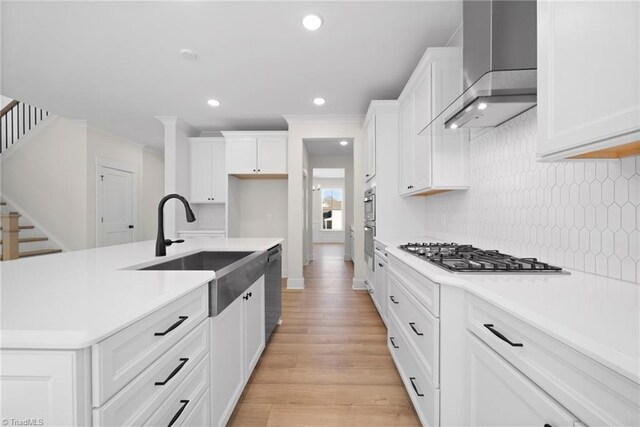 kitchen featuring stainless steel gas cooktop, decorative backsplash, wall chimney exhaust hood, and a sink