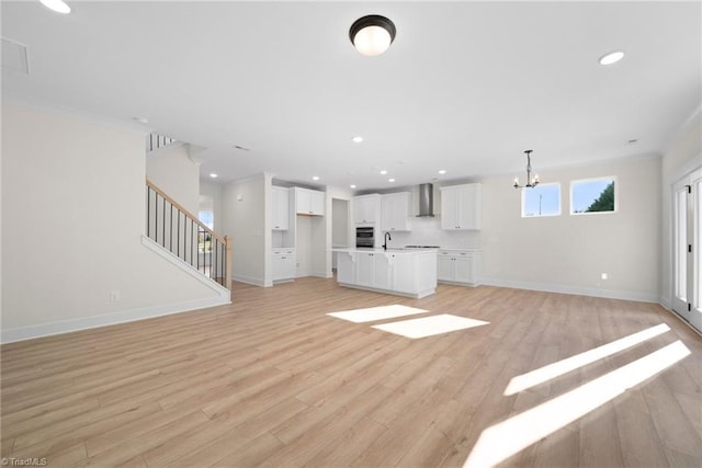 unfurnished living room featuring a sink, light wood-type flooring, baseboards, a notable chandelier, and recessed lighting