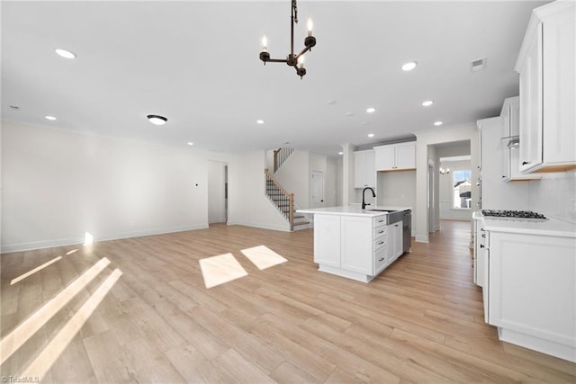 kitchen featuring recessed lighting, visible vents, a sink, open floor plan, and white cabinetry