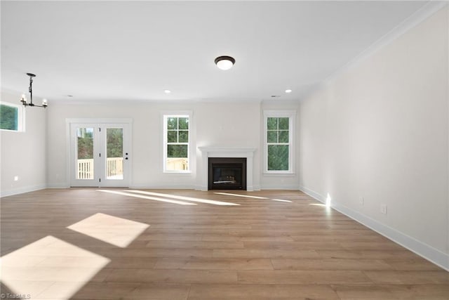 unfurnished living room featuring light wood finished floors, baseboards, a chandelier, and ornamental molding