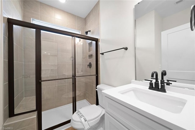 full bathroom featuring a shower stall, toilet, and vanity