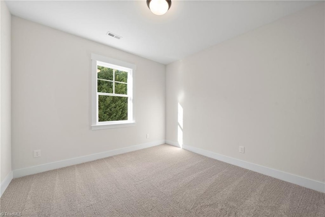 carpeted spare room with visible vents and baseboards