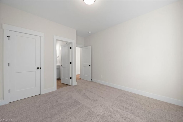 unfurnished bedroom with carpet floors, baseboards, and connected bathroom