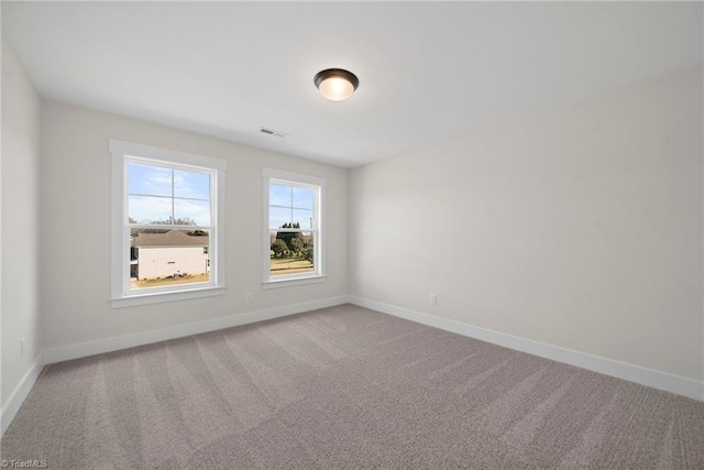 carpeted empty room featuring baseboards and visible vents