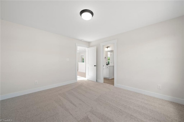 spare room featuring light carpet and baseboards