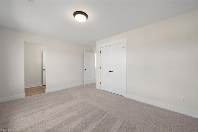 unfurnished bedroom with baseboards, carpet floors, and a closet