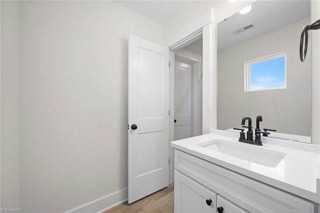 bathroom with baseboards, vanity, wood finished floors, and visible vents
