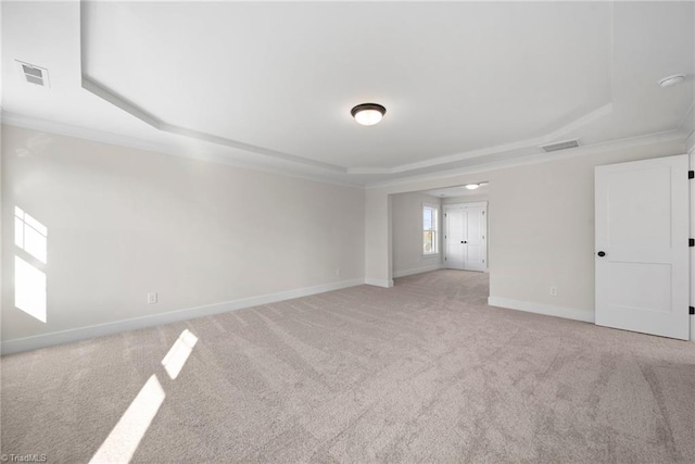 spare room featuring a tray ceiling, baseboards, visible vents, and light colored carpet