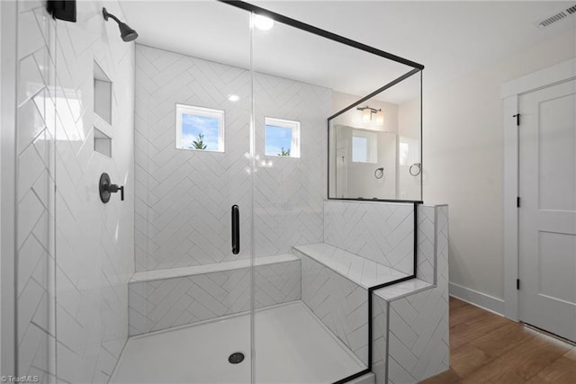 bathroom featuring a shower stall, a wealth of natural light, wood finished floors, and visible vents