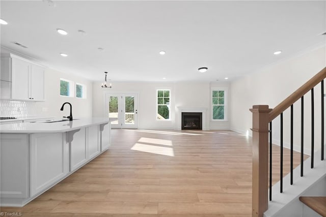 kitchen with a wealth of natural light, white cabinetry, light wood-style floors, and a sink