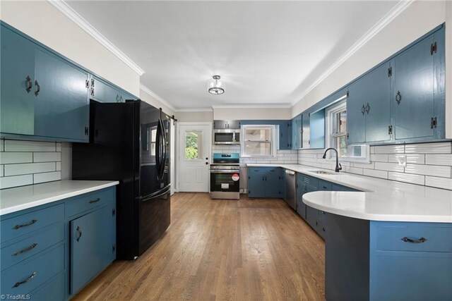 kitchen with appliances with stainless steel finishes, light hardwood / wood-style floors, tasteful backsplash, and sink