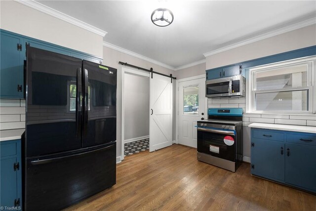 kitchen featuring crown molding, a barn door, appliances with stainless steel finishes, dark hardwood / wood-style flooring, and tasteful backsplash