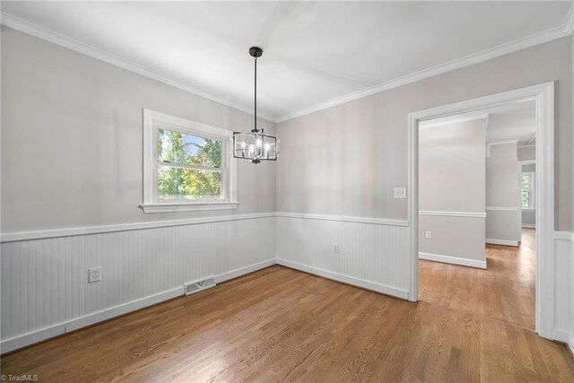 empty room with ornamental molding, hardwood / wood-style flooring, and a notable chandelier