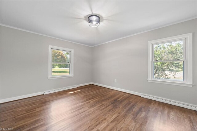 spare room with plenty of natural light, baseboard heating, ornamental molding, and hardwood / wood-style floors