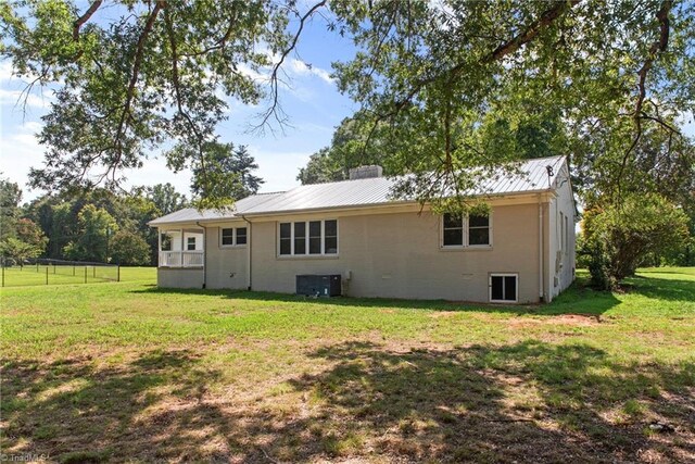 back of house featuring a lawn and central air condition unit