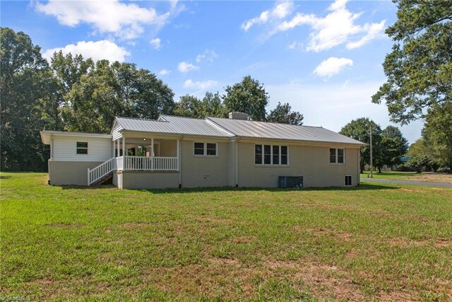 back of property featuring a lawn and central AC