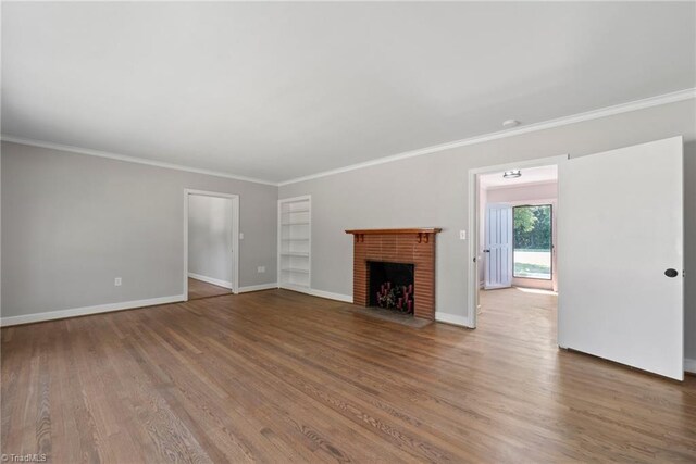 unfurnished living room with ornamental molding, wood-type flooring, and a brick fireplace