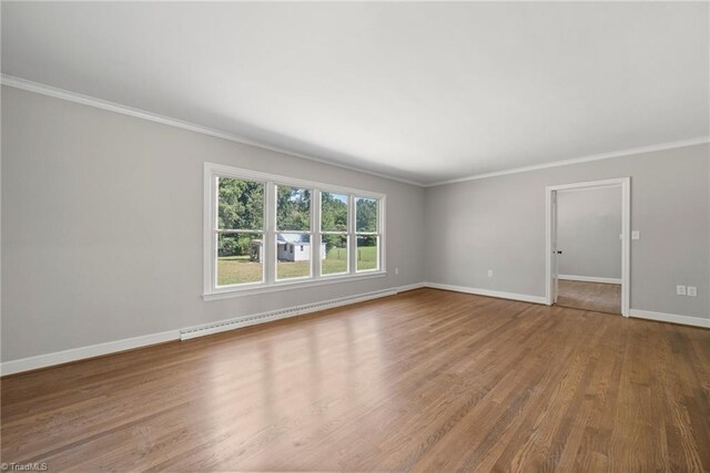 unfurnished room with hardwood / wood-style floors, baseboard heating, and ornamental molding