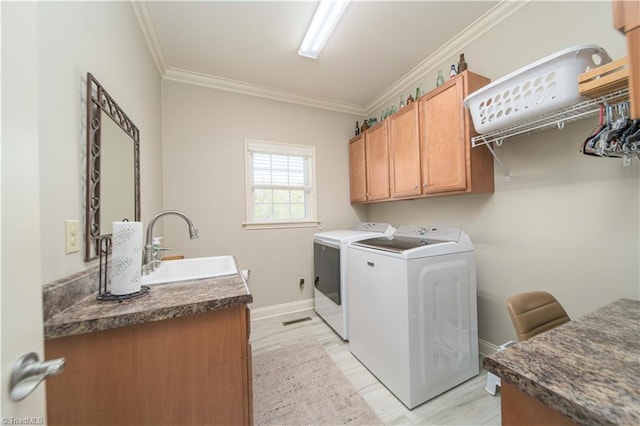 clothes washing area featuring ornamental molding, a sink, independent washer and dryer, baseboards, and cabinet space