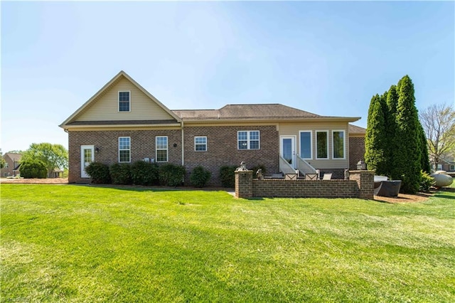 rear view of house with brick siding, entry steps, and a lawn