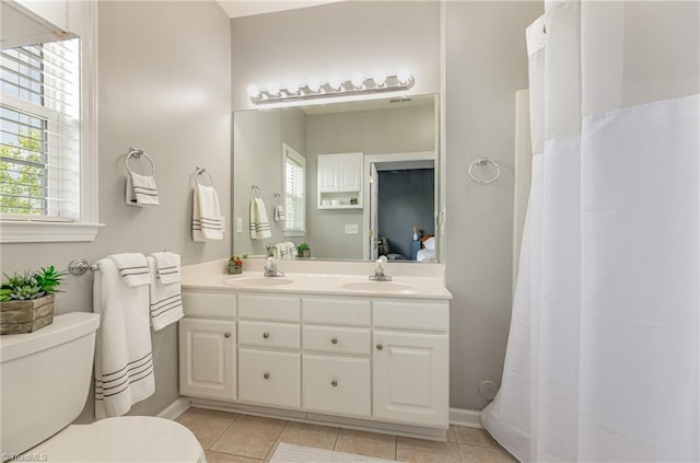 bathroom featuring double vanity, toilet, a sink, and tile patterned flooring