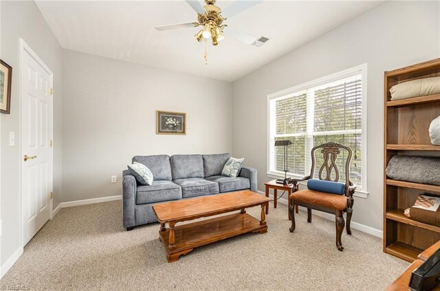 living area with light colored carpet, ceiling fan, visible vents, and baseboards