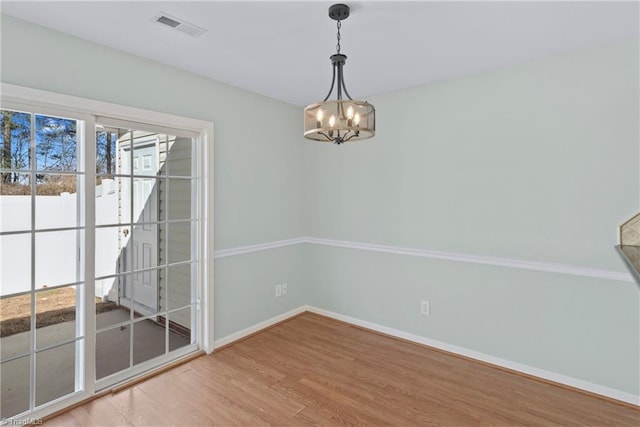 spare room featuring visible vents, baseboards, a notable chandelier, and light wood finished floors