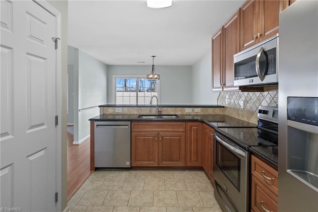 kitchen with a peninsula, a sink, decorative backsplash, appliances with stainless steel finishes, and brown cabinets