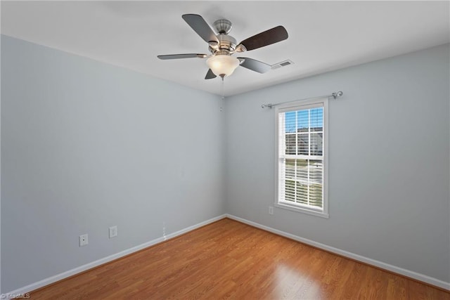 unfurnished room featuring ceiling fan, visible vents, baseboards, and wood finished floors