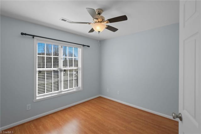 unfurnished room with visible vents, a ceiling fan, baseboards, and wood finished floors