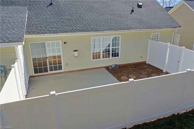 rear view of house with a patio area, a fenced backyard, and a shingled roof