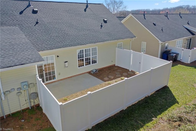 back of house with a patio, a yard, a fenced backyard, and a shingled roof