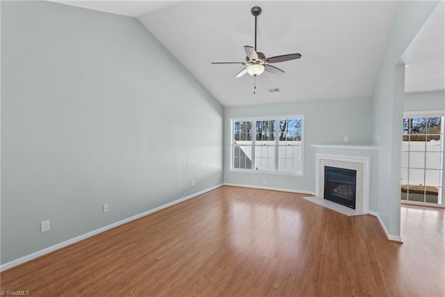 unfurnished living room featuring visible vents, ceiling fan, a tiled fireplace, lofted ceiling, and wood finished floors