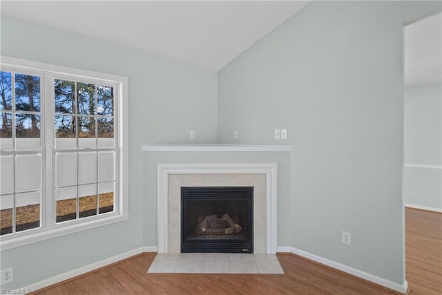 unfurnished living room with a healthy amount of sunlight, a fireplace, baseboards, and wood finished floors