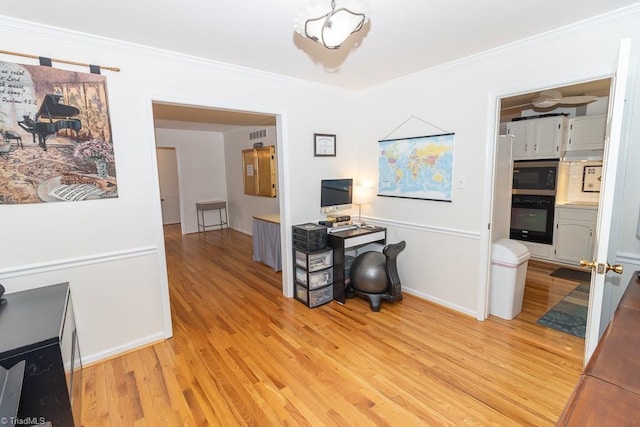 home office with crown molding and light hardwood / wood-style floors