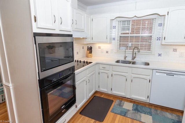 kitchen with white cabinetry, sink, tasteful backsplash, premium range hood, and black appliances