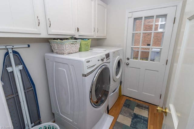 clothes washing area with cabinets, light hardwood / wood-style flooring, and washing machine and clothes dryer