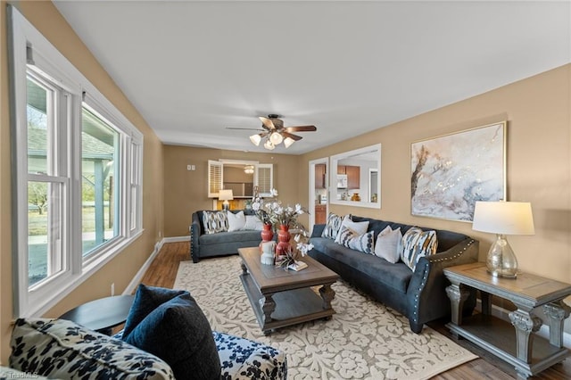 living area with ceiling fan, wood finished floors, and baseboards