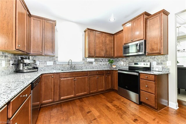 kitchen with light stone counters, sink, tasteful backsplash, dark wood-type flooring, and stainless steel appliances