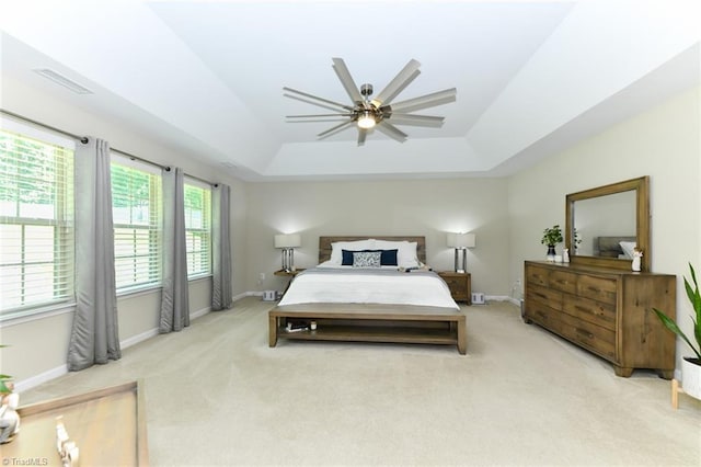 bedroom with light carpet, a tray ceiling, and ceiling fan