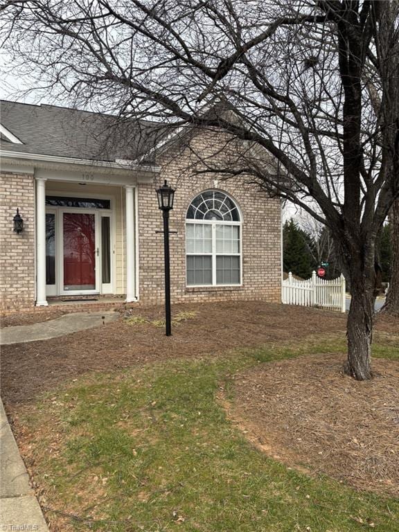 doorway to property with fence and brick siding