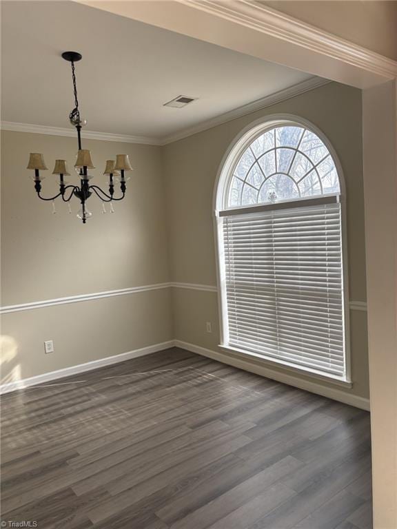 spare room with a chandelier, dark wood-style flooring, visible vents, and crown molding